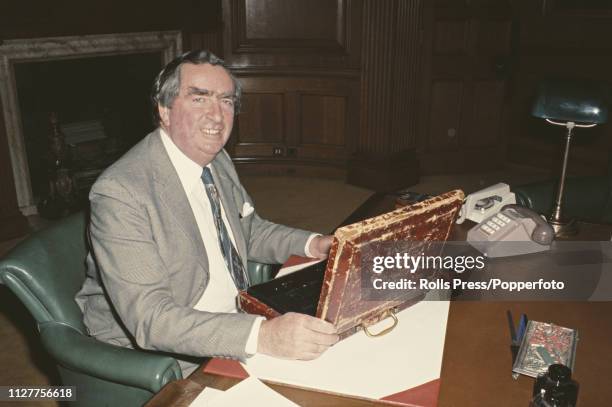 British Labour Party politician and Chancellor of the Exchequer, Denis Healey pictured with Gladstone's budget box on his desk in the Treasury in...