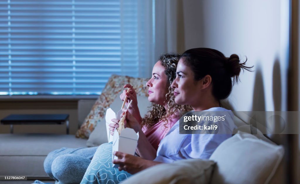 Tirar irmãs hispânicas no sofá comendo, assistindo tv