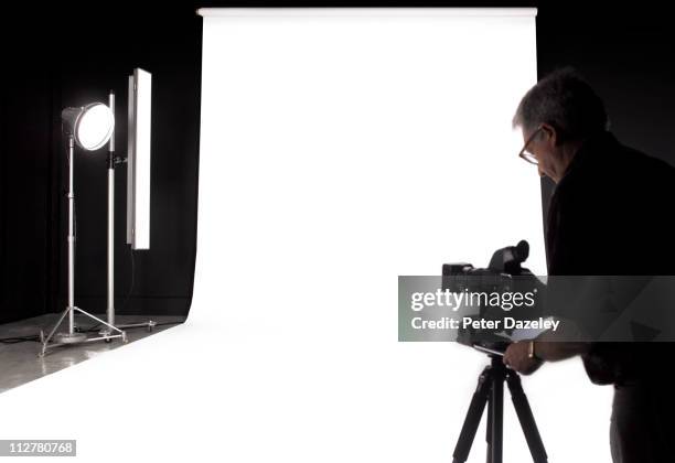 photographer setting up digital camera in studio - photo shoot stockfoto's en -beelden