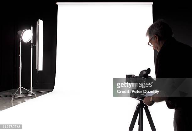 photographer setting up digital camera in studio - camera white background stock pictures, royalty-free photos & images