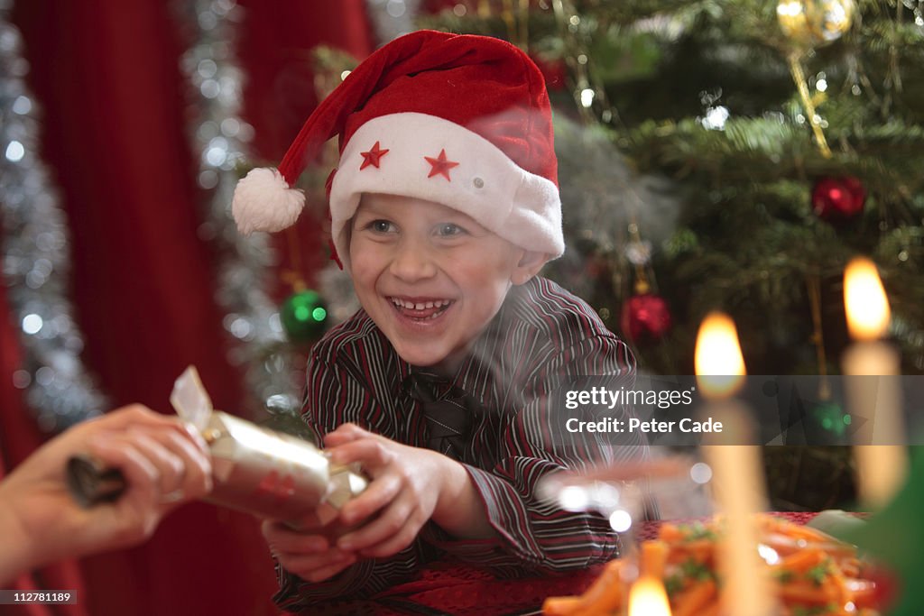 Young boy pulling cracker at christmas table