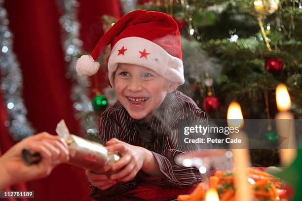 young boy pulling cracker at christmas table - 聖誕拉炮 個照片及圖片檔