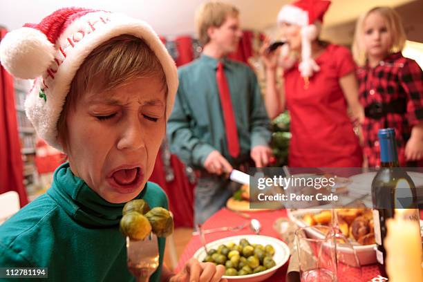 boy tasting sprouts at christmas table - sojabohnensprosse stock-fotos und bilder