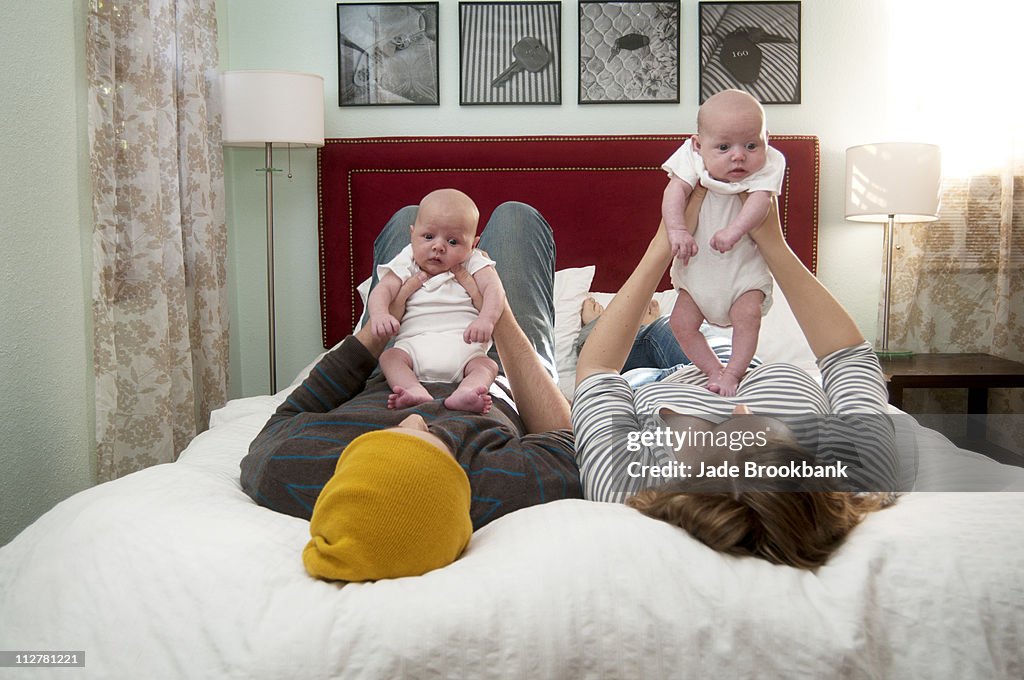 Family playing with newborn twins in bed