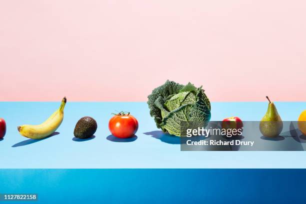 a row of different fruits and vegetables on a table top - still life foto e immagini stock