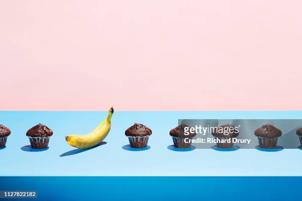 a banana in a row of chocolate cupcakes - temptation stock pictures, royalty-free photos & images