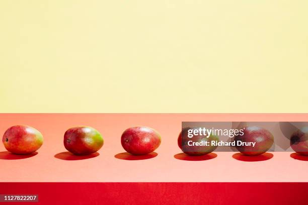 a row of mangos on a table top - raw mango stockfoto's en -beelden