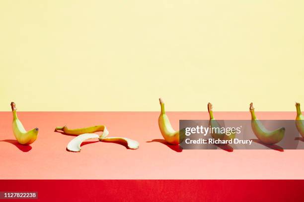 a banana skin in a row of bananas - banana skin stock-fotos und bilder