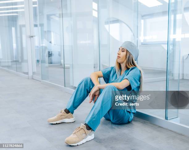 tired female medical professional taking break in hospital corridor - nurse resting stock pictures, royalty-free photos & images