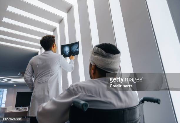 junger arzt mann sucht röntgen des schädels der patient - head injury stock-fotos und bilder