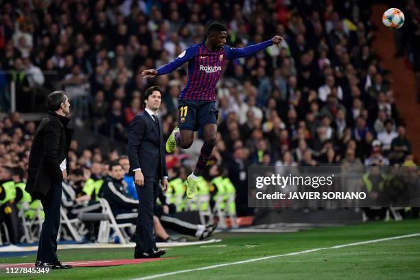 Barcelona's French forward Ousmane Dembele jumps close to Barcelona's Spanish coach Ernesto Valverde and Real Madrid's Argentinian coach Santiago...