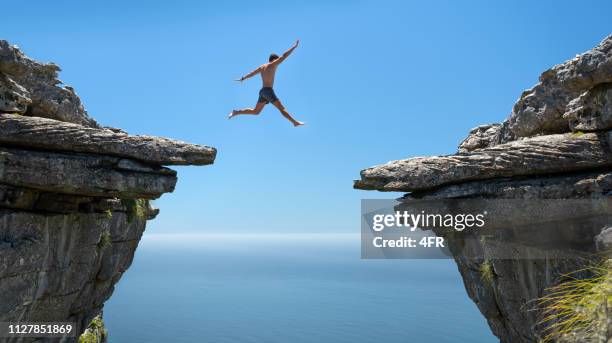 jumping the gap, believe in yourself - cliff gap stock pictures, royalty-free photos & images