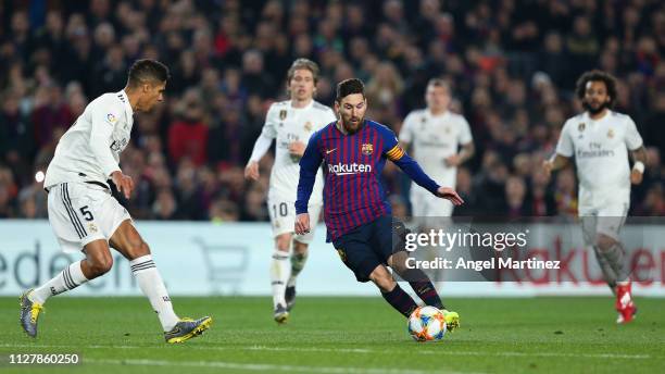 Lionel Messi of FC Barcelona competes for the ball with Raphael Varane of Real Madrid CF during the Copa del Semi Final first leg match between...