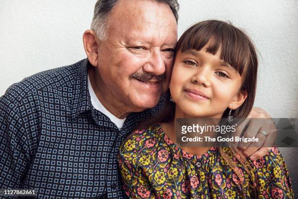 smiling grandfather embracing granddaughter - wange an wange stock-fotos und bilder