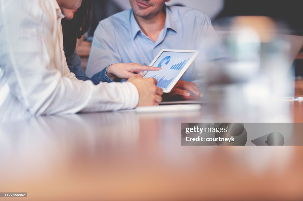 Mensen uit het bedrijfsleven bezig met financiële gegevens op een digitale tablet.