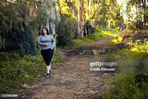 plus size women jogging and exercising at the park - läufer dramatisch stock-fotos und bilder