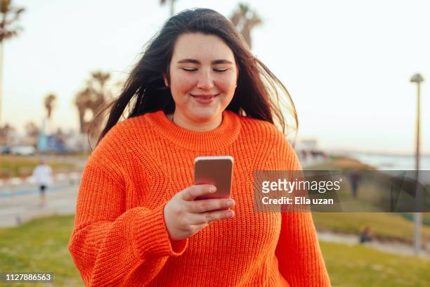 plus size girl texting outdoors - chicas gorditas fotografías e imágenes de stock