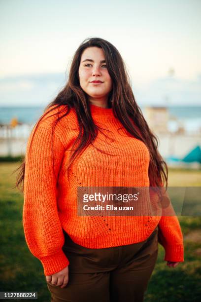 portrait of plus size woman standing in the park - overgewicht vrouw stockfoto's en -beelden