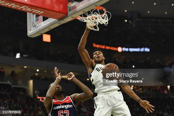 Giannis Antetokounmpo of the Milwaukee Bucks dunks in front of Jordan McRae of the Washington Wizards during the first half of a game at Fiserv Forum...
