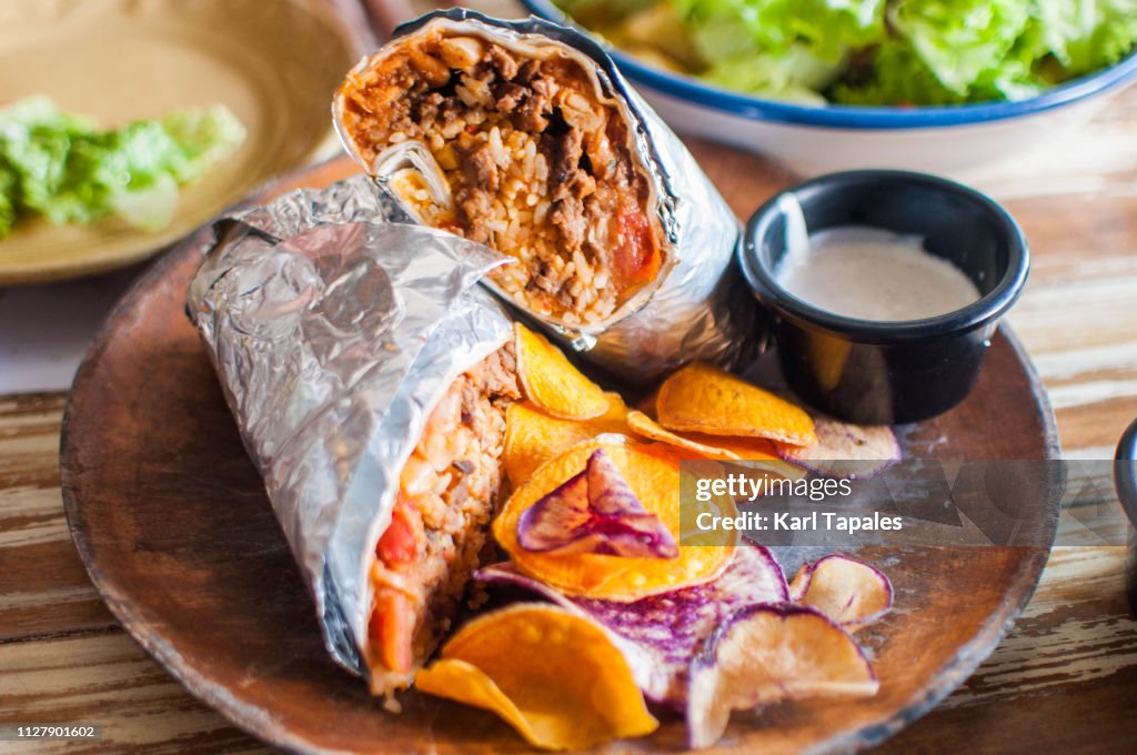 A close-up of burritos on a wooden plate