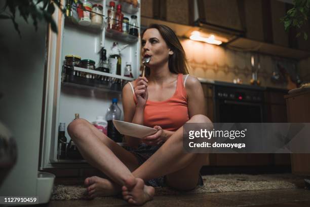 mujer buscando midnight snack en el refrigerador - hambre fotografías e imágenes de stock