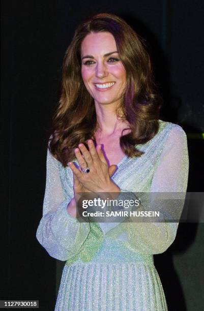 Britain's Catherine, Duchess of Cambridge reacts as her husband Prince William talks during their visit to the Empire Music Hall in Belfast, Northern...