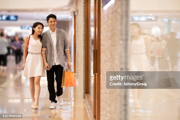 couple walking through shopping mall - chinese young adults shopping imagens e fotografias de stock