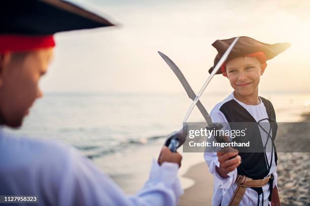 jongetjes spelen pirates op een strand - duelleren stockfoto's en -beelden