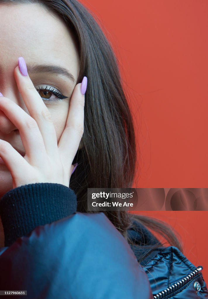 Young woman peeking through fingers.