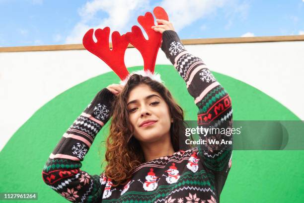 woman wearing festive antlers and christmas sweater - suéter natalino - fotografias e filmes do acervo