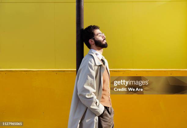 young man leaning on street sign holding face up to sun. - london fashion stock-fotos und bilder