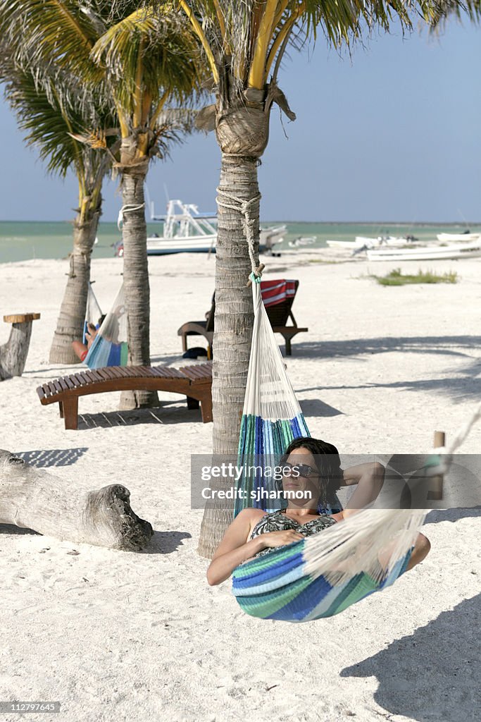 Bela jovem relaxante na cama de rede na praia Tropical Paradise