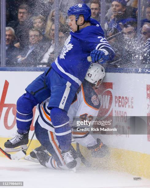 Edmonton Oilers right wing Josh Currie ends up on the losing end of a crunch into the corner with Toronto Maple Leafs defenseman Travis Dermott ....