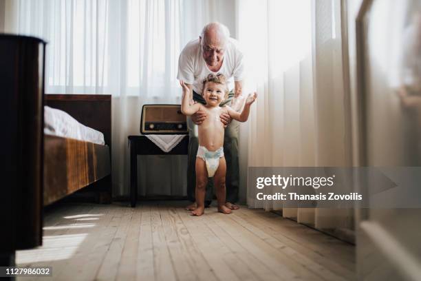 grandfarher helping his grandson to walk - bébé rire photos et images de collection