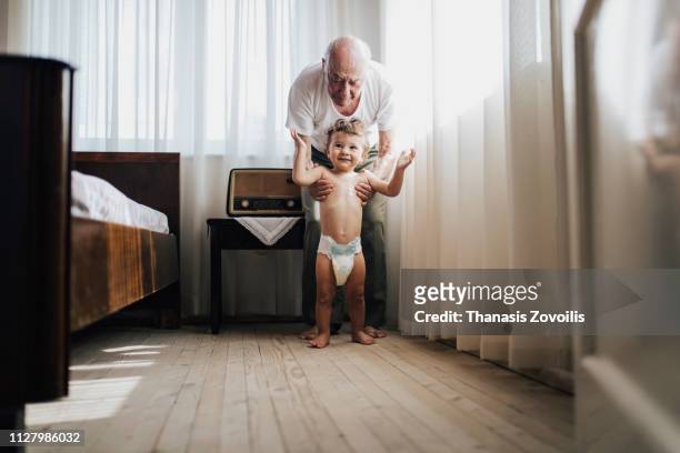 grandfarher helping his grandson to walk - grandfather stock pictures, royalty-free photos & images