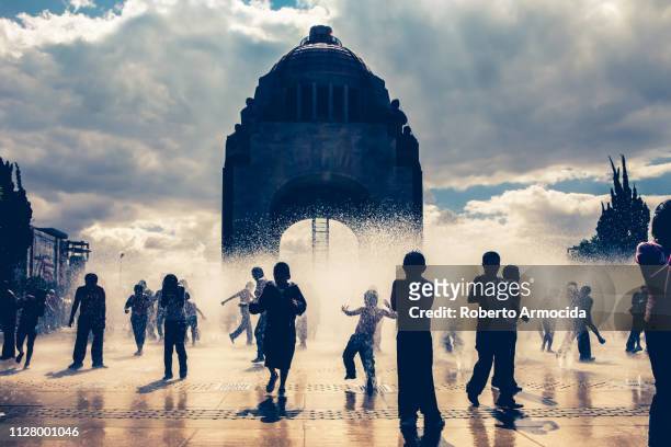 dozens of kids play and cool off in the floor fountains of the monumento a la revolucion in the heart of mexico city - mexican revolution imagens e fotografias de stock