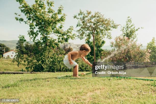 niño jugando con regadera de agua - water garden fotografías e imágenes de stock