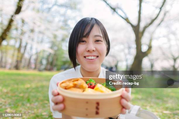 ung kvinna ha picknick under sakura träd - medhavd lunch bildbanksfoton och bilder