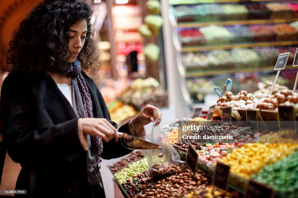 Ung kvinna shopping i marmeladkonfekt butik i Grand Bazaar, Istanbul, Turkiet