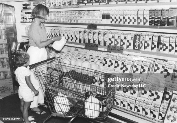 Woman and her daughter stand next to the dairy aisle selecting gallons of milk at Key Food market on Grand Ave. In Baldwin, New York on Sept. 21,...