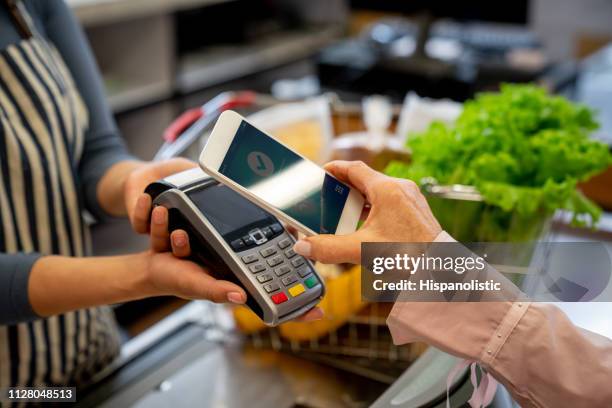 cliente mujer irreconocible pagar compras con smartphone - pago por móvil fotografías e imágenes de stock