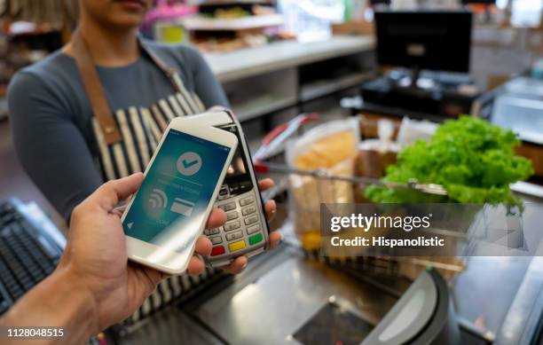 unrecognizable customer paying for groceries at supermarket using his smartphone - counter intelligence stock pictures, royalty-free photos & images