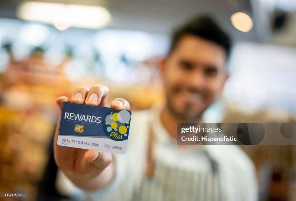 Salesman at a grocery store holding a loyalty program card up front