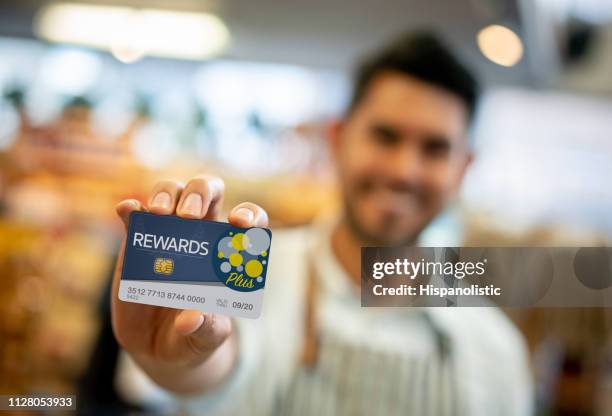 salesman at a grocery store holding a loyalty program card up front - retail loyalty stock pictures, royalty-free photos & images