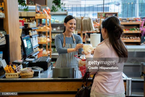 onherkenbaar klant bij supermarkt inleveren van producten naar vriendelijke kassa voor afhandeling - supermarket register stockfoto's en -beelden