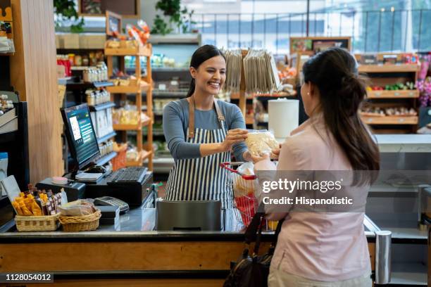 超市的無法辨認的客戶將產品交給友好的收銀員結帳 - cashier 個照片及圖片檔