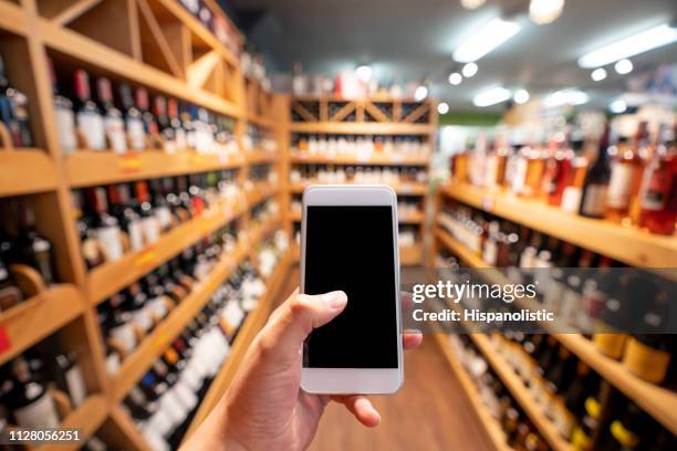 personne méconnaissable qui détient un smartphone à une cave à vin - vignerons photos et images de collection