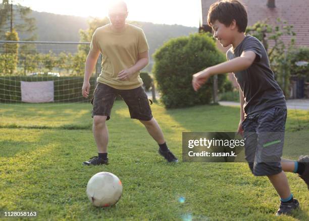 father and son playing soccer in the backyard. - 8 ball stock-fotos und bilder