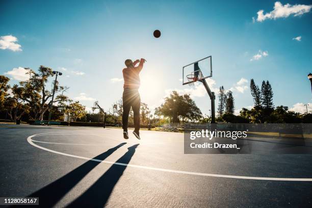 latino guy shooting basketball on the court in usa in summer - making a basket stock pictures, royalty-free photos & images