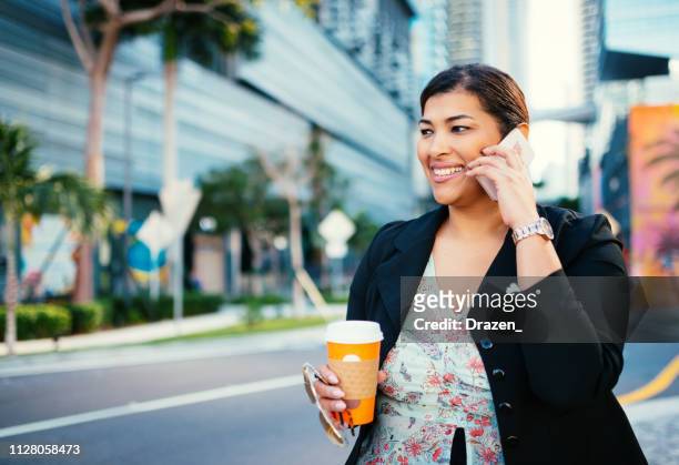 mature latina businesswoman using smart phone in the financial district in usa - miami business imagens e fotografias de stock